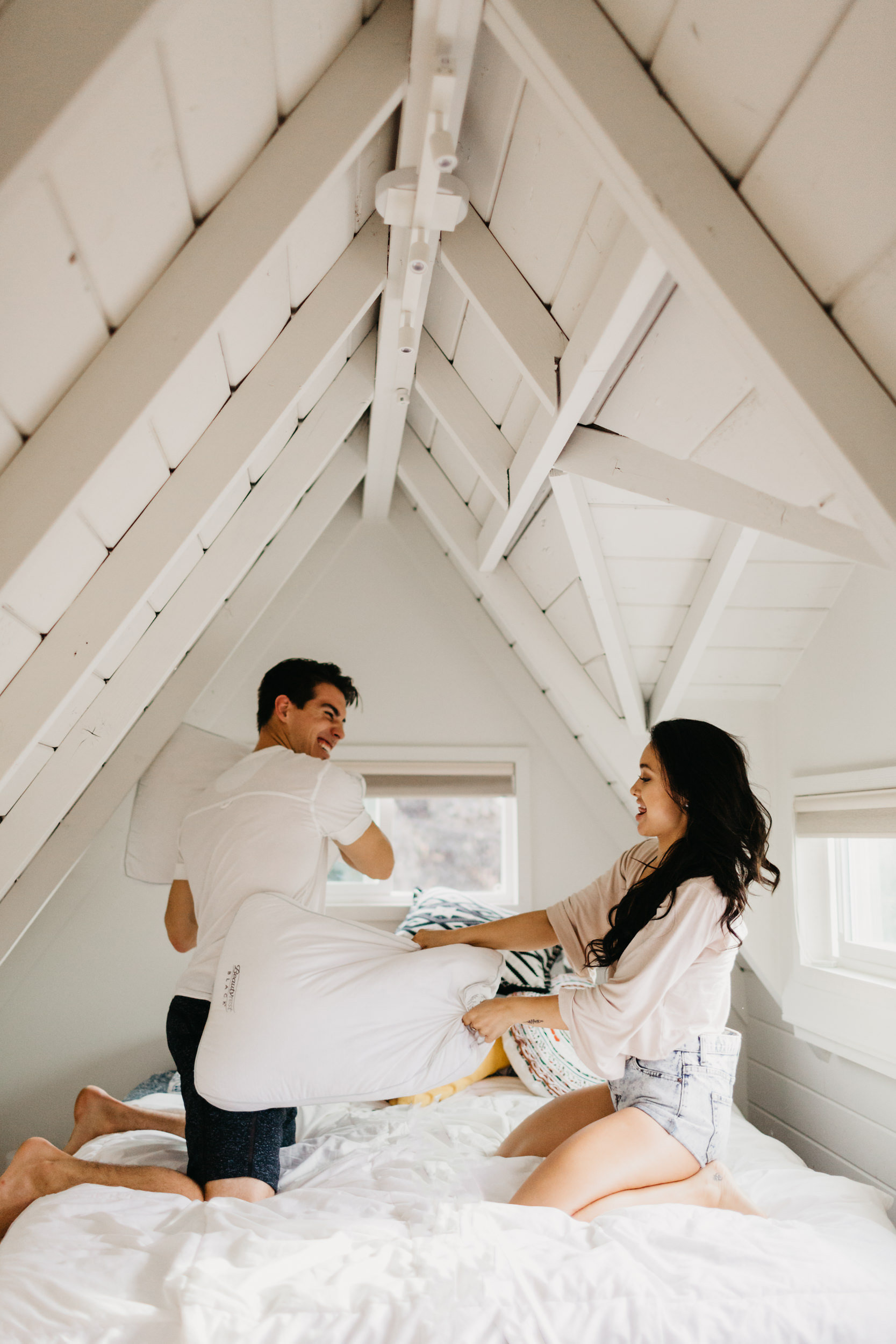 couple playing with pillows in bed