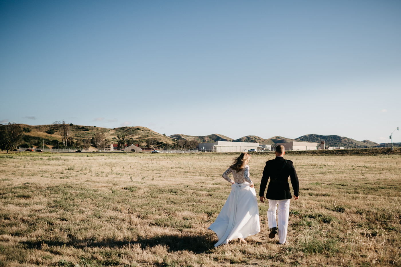 bride and groom running in field
