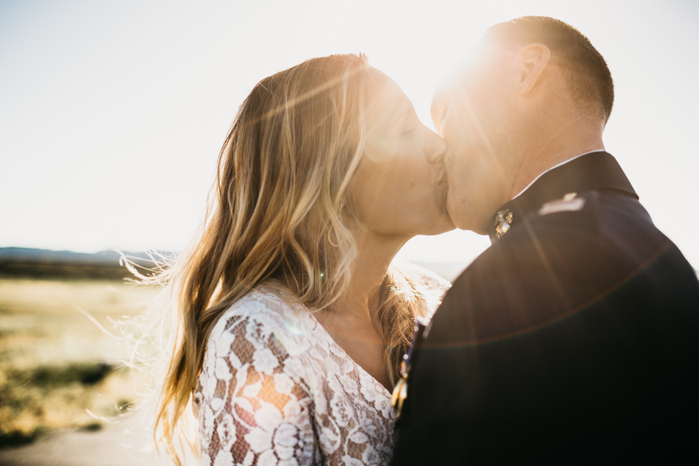 bride and groom kissing sun flare