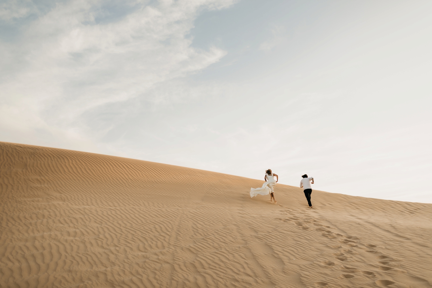 couple running in glamis sand dunes 